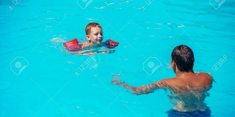 62951707 happy boy enjoying with swimming and splashing with his father happy family playing in blue water
