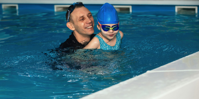 little girl swimming lessons pool with coach